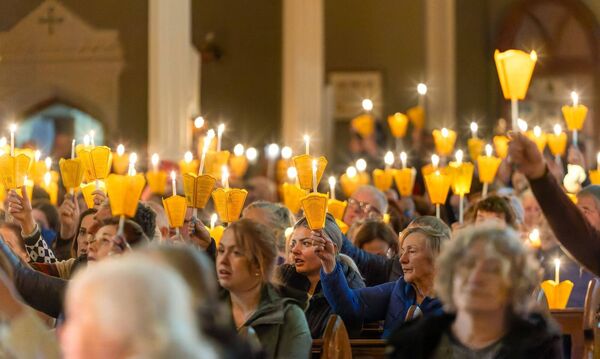 Worshippers hold up their candles in the cathedral