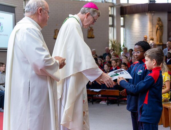 Emma and Eric present the school crest to Bishop Denis Nulty