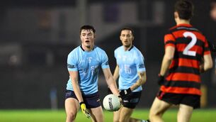 <p>Adam Burgess operating at midfield for SETU Carlow gets ready to give a handpass against Trinity.</p>