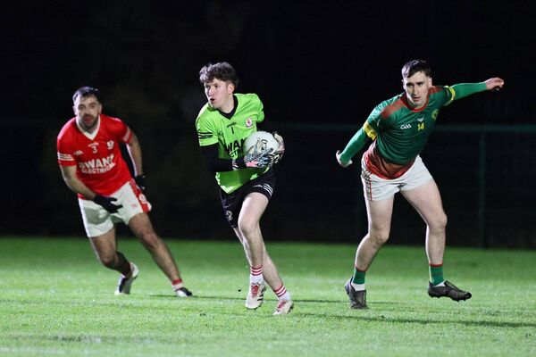 Eire Og goalkeeper Ben McCarron strides forward from his line, ball in hand.