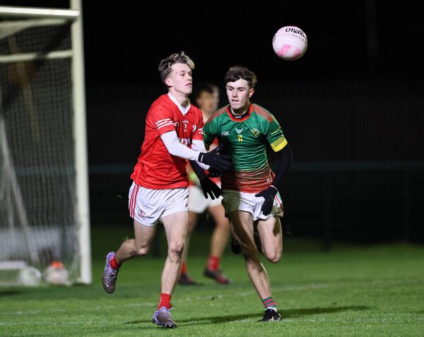 Eire Og's Alex Donnelly-Finn handpass the ball away from danger with Aedan Byrne (Michael Davitts) for company.