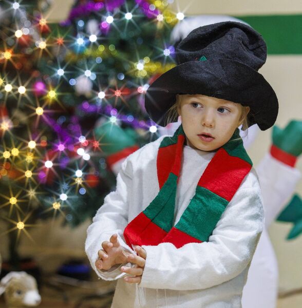 A young child dressed as a snowman sizes up the audience before their performance 