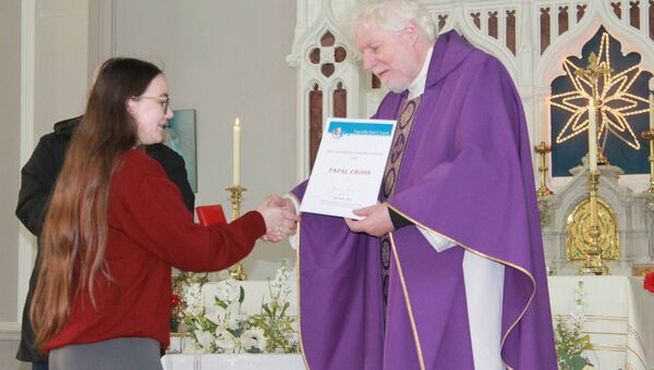 Sarah receiving her award from Fr Tom Kennedy 