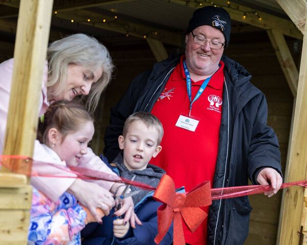 Two pupils help Ms Dempsey and John Morris with the ribbon cutting 