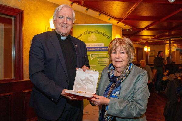 An tAthair Conn Ó maoldomhnaigh congratulates Caitlín Mhic Cárthaigh, retired principal of Gaelcholáiste Cheatharlach on being awarded the Bene Merenti medal recently An tAthair Conn Ó maoldomhnaigh congratulates Caitlín Mhic Cárthaigh, retired principal of Gaelcholáiste Cheatharlach on being awarded the Bene Merenti medal recently