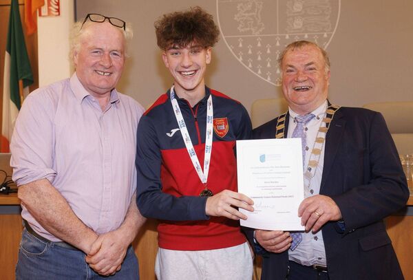 Cllr Ken Murnane makes a presentation to Harry Butcher, a gold medalist in the U14 hurdles event in the National Community Games. Also shown is cllr Charlie Murphy