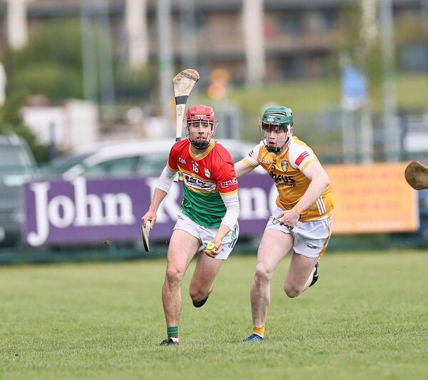 Mark Dundon thunders out of defence, with Antrim's Oisin McCallin giving chase.