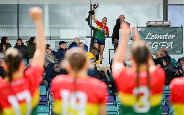 Carlow captain Roisin Bailey lifts the trophy as her teammates cheer her on.